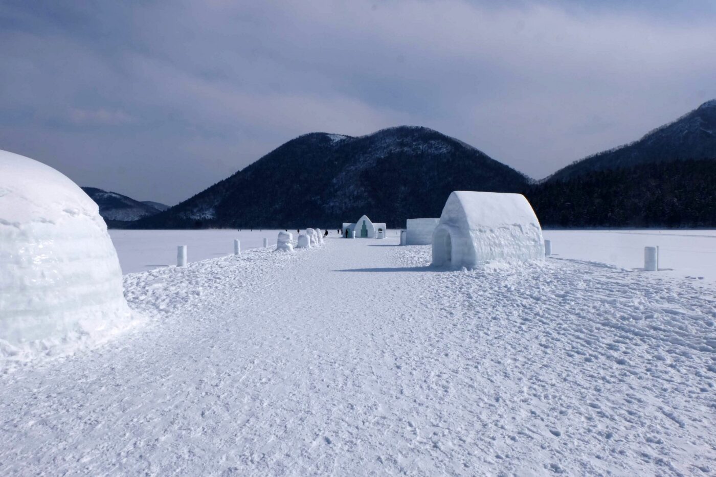 十勝・然別湖の氷上に広がる雪の村、氷のイグルーと山並みの冬景色